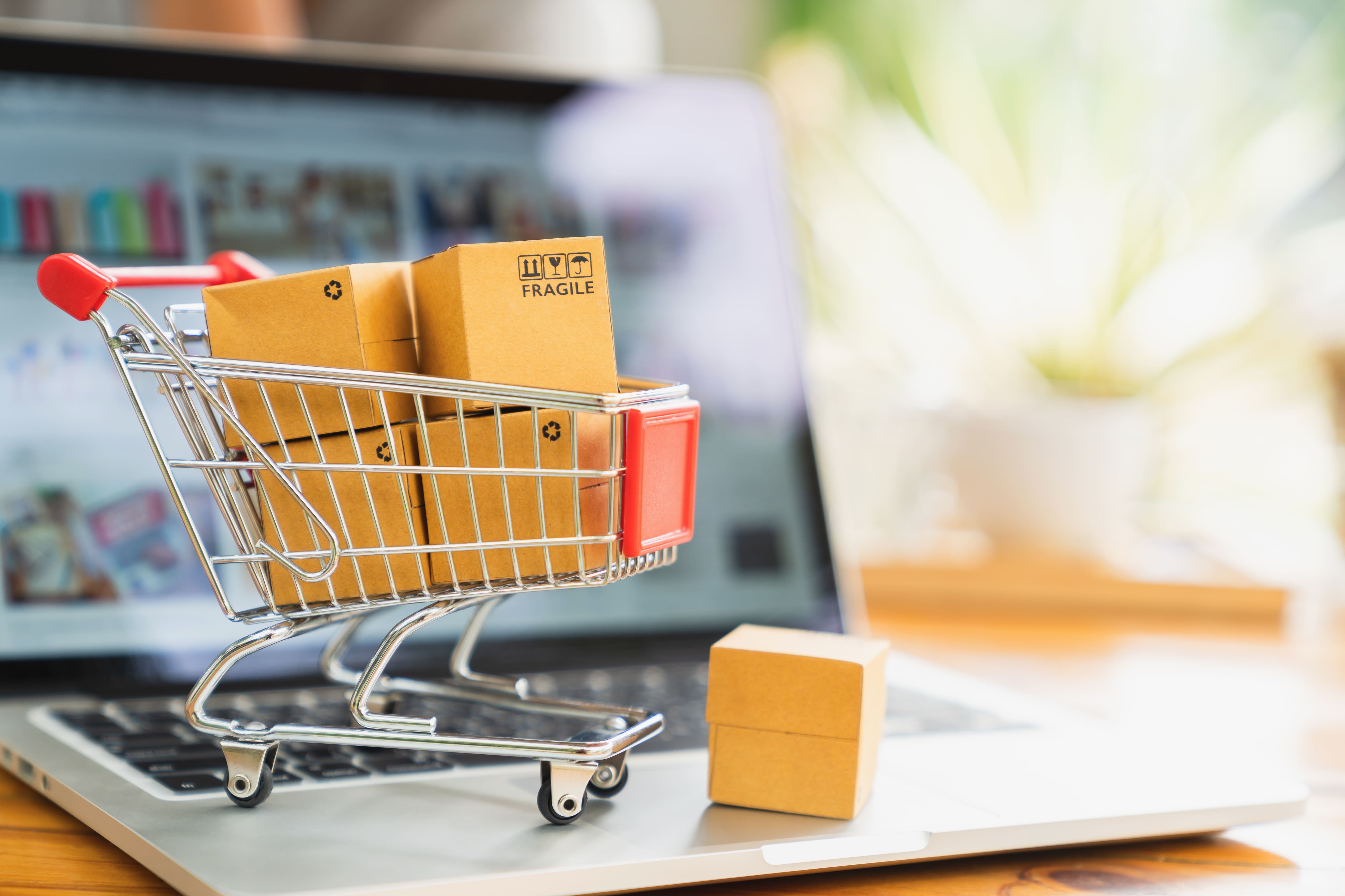 online-shopping-delivery-concept-product-package-boxes-cart-laptop