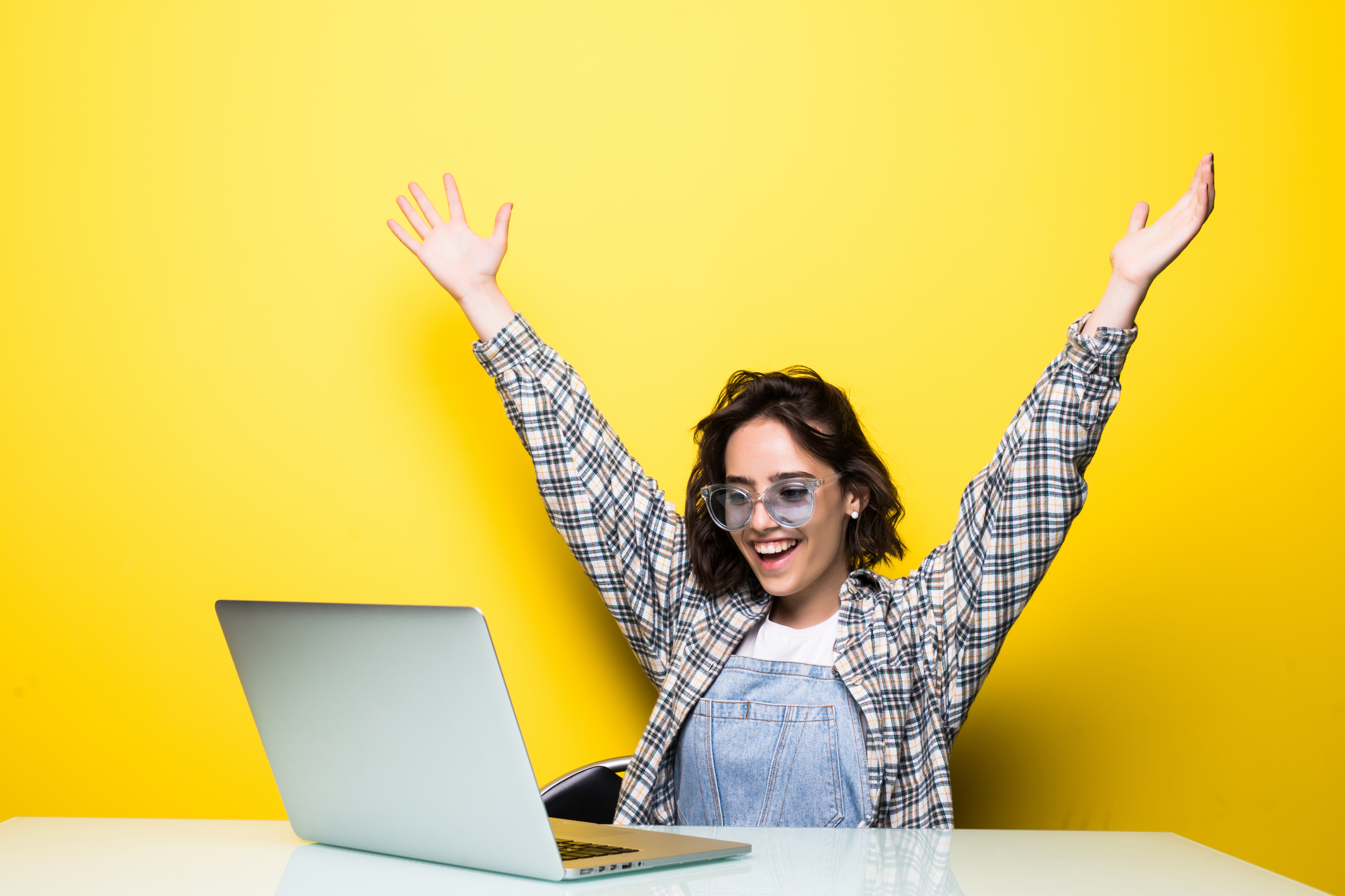 cheerful-pretty-woman-glasses-holding-laptop-showing-fist-up-excited-with-win